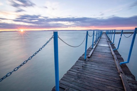 Water landscape, taken from the shore of a calm lake. View over the reflecting water to the horizon