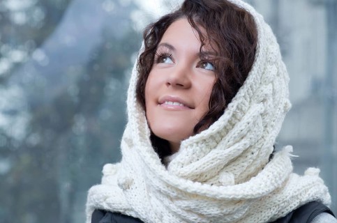 Pretty young caucasian brunette woman wearing white scarf with hood in a outdoor winter portrait