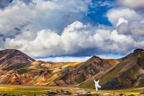 The elderly woman carries out pose of Tree in yoga among thermal sources. The picturesque valley in