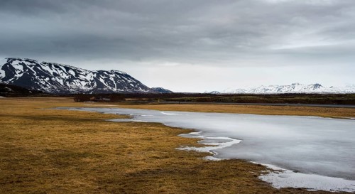 Typical Icelandic dramatic landscape with frozen lake and mountains covered in snow in Iceland
