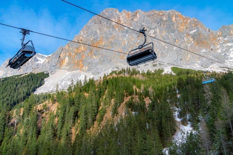 Alpine scenery with the rocky peaks of the Alps mountains and ski lifts rolling on a cableway over