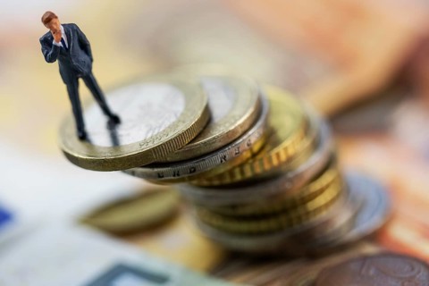 Figure of a thoughtful businessman between euro coins, studio shot, Germany, Europe