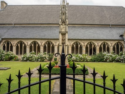 A well-kept courtyard with Gothic architecture, flower beds and a decorative fence in the