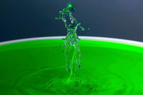 A powerful splash of green liquid with eye-catching water sculptures, water droplets, collision,