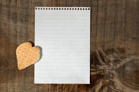 Heart shape cookie on wooden background and white paper sheet