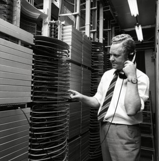 Telephony in the 1970s. A man in a room with an automatic switchboard connecting the calls through