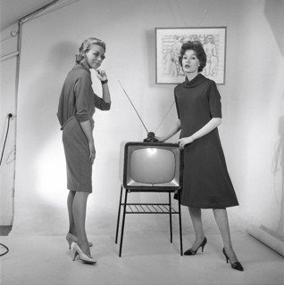 Television in the 1950s. Two young women are standing dressed in a typical 50s dress beside a