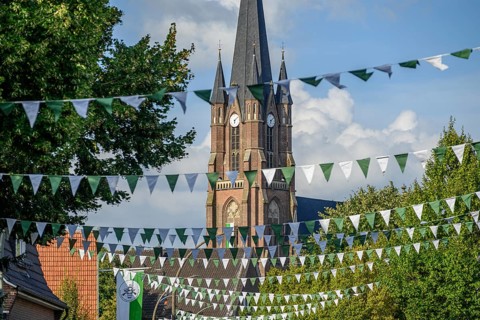 Church with high tower and flags, surrounded by trees, borken, münsterland, germany