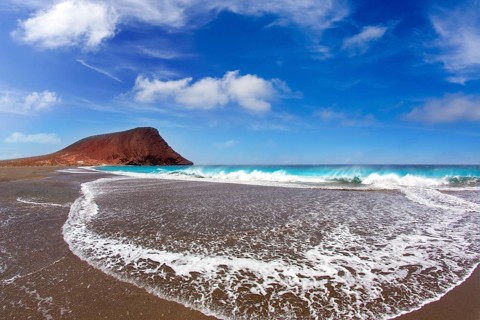 Beach Playa de la Tejita turquoise in Tenerife Canary islands with red mountain