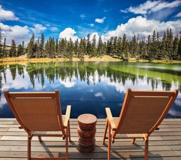 Two wooden deckchairs for tourists on ashore shallow round lake. Autumn day in Jasper National Park