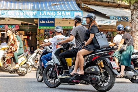 People ride scooters through a busy city shopping street during the day, people on scooters ride