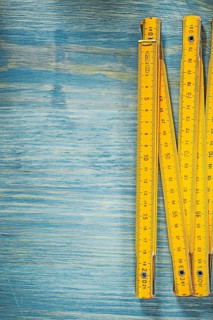 Yellow wooden meter on vintage wood surface construction concept