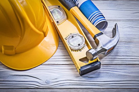 Claw hammer building helmet blue rolled engineering drawings construction level on wooden board