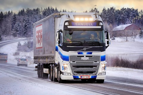 Blue white Volvo FH semi trailer truck Kuljetusliike Harri Sandell Oy with bright headlights on