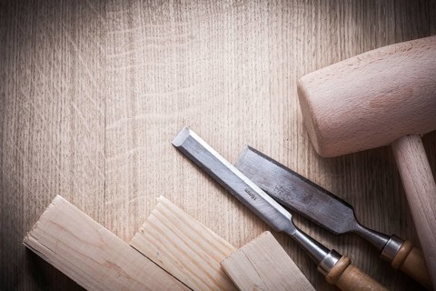 Wooden bricks mallets flat chisels on wood background close up view construction concept
