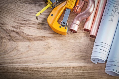 Blueprints tape measure water pipe cutter fittings on wooden board plumbing concept