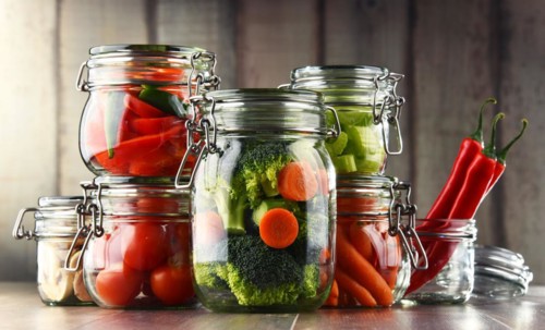 Jars with marinated food and organic raw vegetables