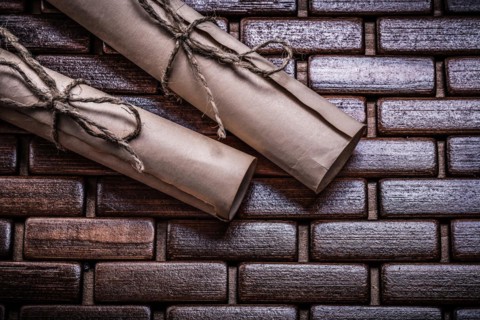 Antique paper rolls with string on a wicker placemat