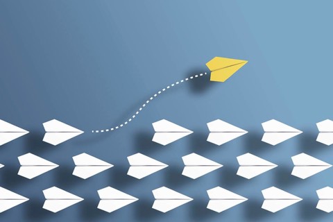 paper planes in a row on blue background and one paper glider going in different direction,