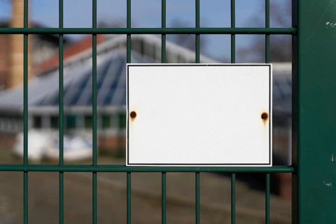 Unlabelled white sign on a fence with space for text
