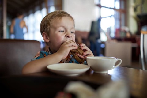 Little boy in a cafe eating big tasty sandwich. Hungry child