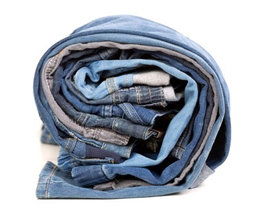 Different jeans rolled up on a white background