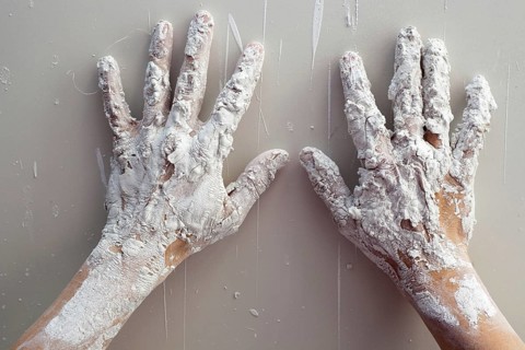 Artist plastering man hands with white dried cracked plaster texture in fingers