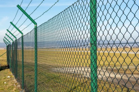 Green steel wire mesh fence around the airport area. Restricted area protection