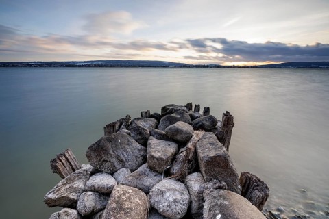 Stone pier jutting into a calm lake, atmospheric clouds in the sky at dusk, calm atmosphere,