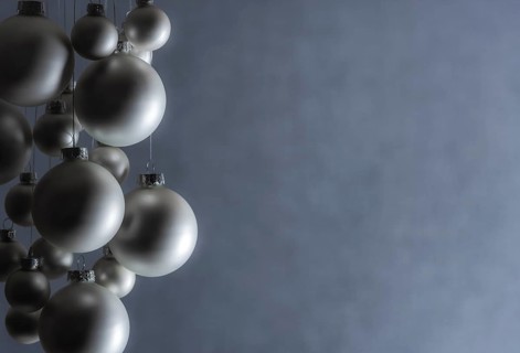 Silver Christmas balls hanged with silver thread, of a matte color, on a gray blurry backdrop,