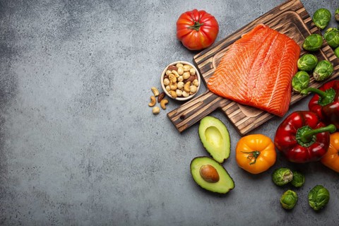 Fresh raw salmon fillet on wooden cutting board, organic bio vegetables and nuts on rustic stone