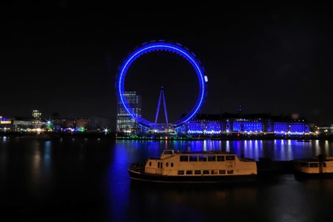 London Eye at night from the north bank with a ship in the foreground