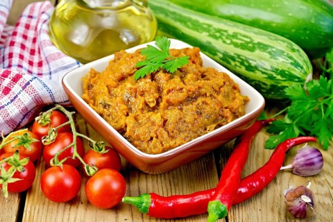 Caviar squash in a clay bowl, tomatoes, red pepper, zucchini, napkin, garlic, vegetable oil on a