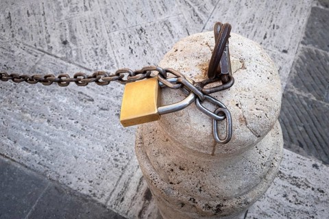 An image of a chain with a lock on a stone pillar