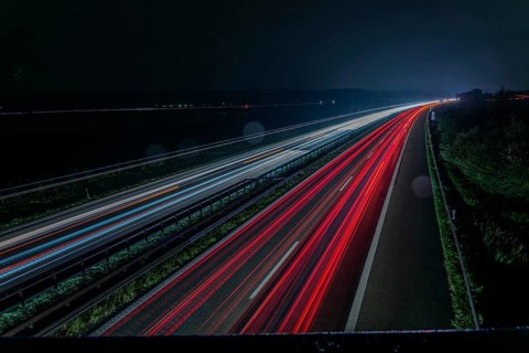 Long exposure of a motorway at night with red and white light trails representing speed and