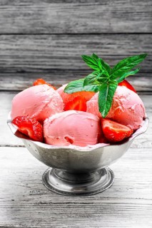Ice cream with strawberries and leaves of mint in the iron bowl