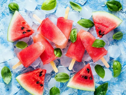 Top view of watermelon and basil popsicles on blue background with fresh green basil leaves and