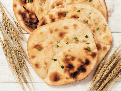 Fresh naan bread on white wooden background with copy space. Top view of several perfect naan