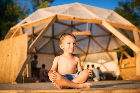 Theme is yoga and children. Caucasian Boy child sitting barefoot cross-legged in lotus position on