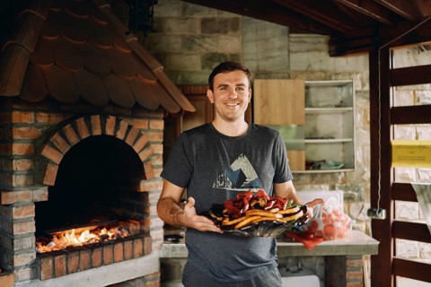 Smiling chef holding big platter with grilled vegetables.