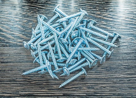 Stack of stainless screws on wooden board