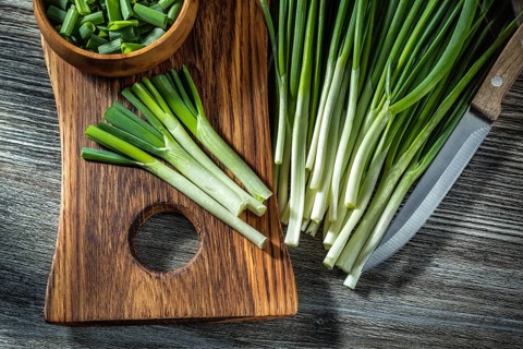 Green chopped onions on wooden cutting board kitchen knife vintage wood background