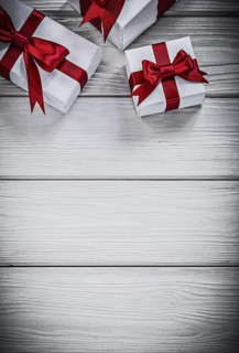Present boxes with red ribbons on wooden board holidays concept