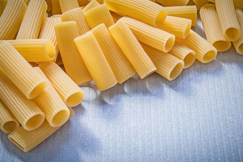 Stack of uncooked pasta on blue background food and drink concept