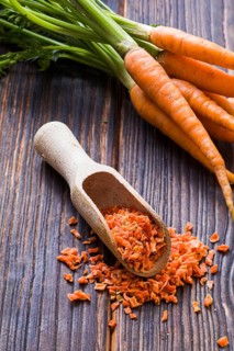Wooden scoop with seasoning made of dried milled carrots. Tasty condiment for cooking. From above