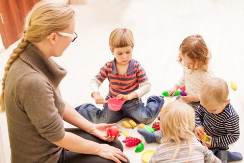 Children with teacher in kindergarten playing cooks