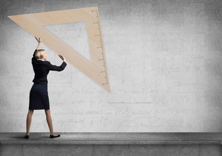 Woman holding big ruler on wall background. Testing and examination concept. Businesswoman