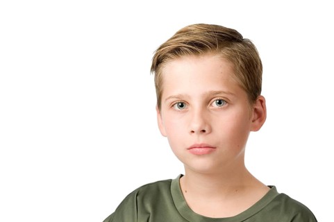Head-and-shoulders portrait of a young male teenager in a T-shirt looking at the camera against a