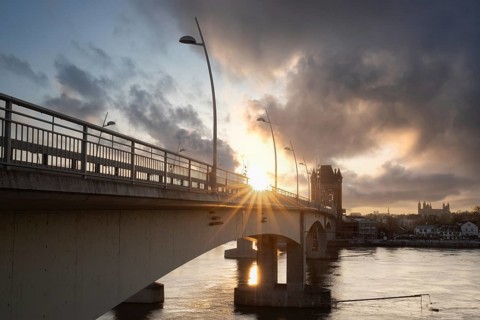 A road or motorway leads through an old historic city gate. Sunset in the evening over the Rhine