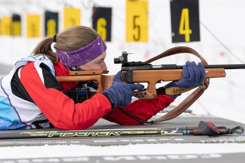 Russian sportswoman biathlete Vakhrusheva Valentina rifle shooting in prone position. Biathlete in
